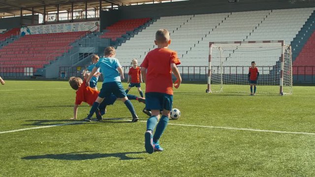 Children playing soccer on arena, attacking and making goal