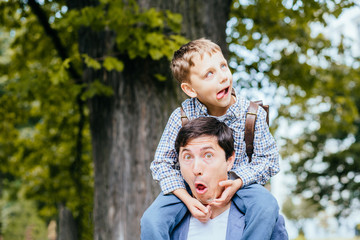 Family portrait of funny joyful child and father, play ape, smile and feels happy. Outdoor shot of...