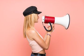 Young blonde woman with hat shouting through a megaphone