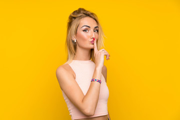 Young blonde woman over isolated yellow wall doing silence gesture