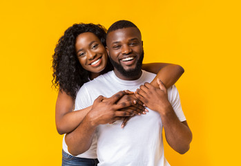 Happy afro woman hugging her man from behind