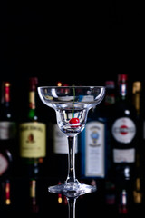 An empty martini glass stands on the bar in the restaurant, on a blurry background of alcohol