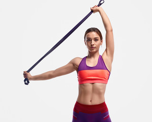 Muscular lady exercising with resistance band