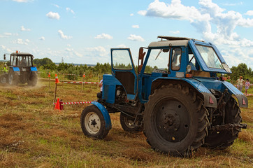 Kostivtsi, Ukraine-July 13, 2019: Figure piloting competition at the field. Blue old tractor is waiting for it attempt. Next participant is ready to start. Festival Brusviana