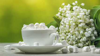 Spring still-life - marshmallows on the background of a bouquet of lilies of the valley, closeup