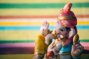 ceramic Ganesha statue rainbow floor background 
