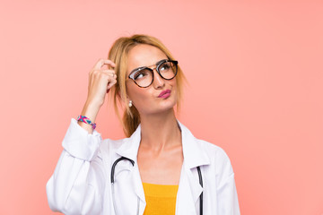 Young blonde doctor woman having doubts and with confuse face expression