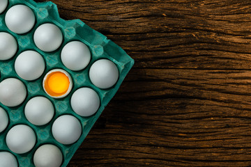 Many white chicken eggs in tray box. Old wood background space for text background space for text. Egg broken in half.