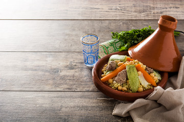 Traditional tajine with vegetables, chickpeas, meat and couscous on wooden table. Copyspace