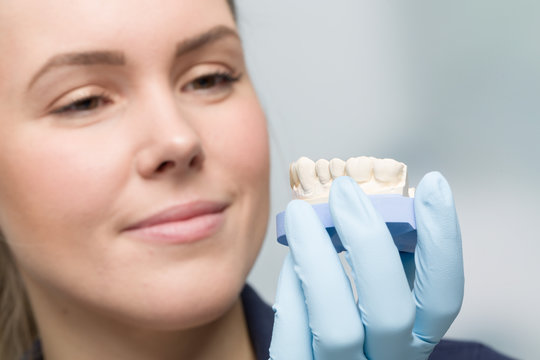 female dental technician cheks quality of an artificial dention