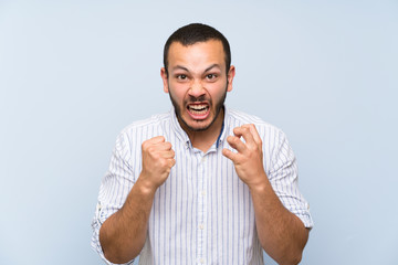 Colombian man over isolated blue wall frustrated by a bad situation
