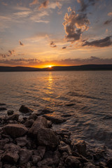 Obraz premium The water at sunset touches the stones