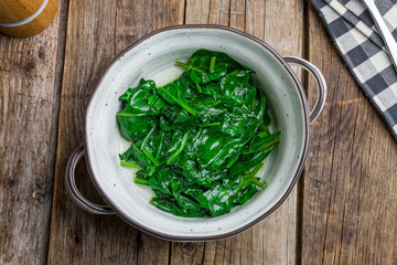 Garnish steamed spinach on wooden table
