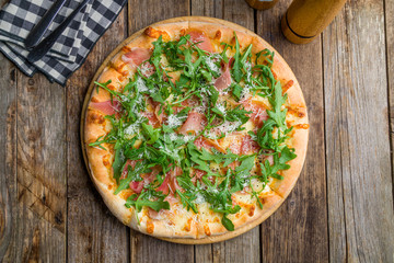Pizza with Parma ham and arugula on wooden table