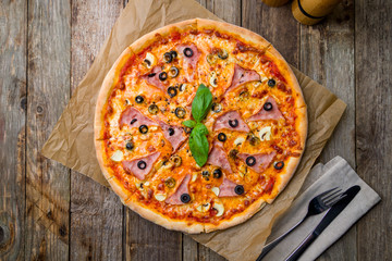 Capricciosa pizza with artichokes on wooden table