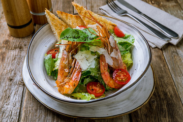salad caesar with shrimps on wooden table