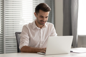 Smiling male entrepreneur working on computer sit at office desk