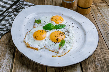 Fried eggs with basyl on wooden table