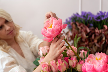 Hands of a beautiful young florist woman making modern bouquet of different flowers
