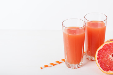Grapefruit refreshing juice with straws on a white background with grapefruit slices. Summer refreshing diet drink, healthy food. Copy space.