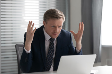 Annoyed mad businessman wearing suit frustrated with computer problem