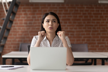 Stressed asian businesswoman clenching fists concerned about business problem