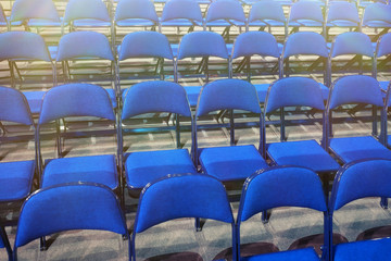 Many blue chairs stand in a row before the event. Toned