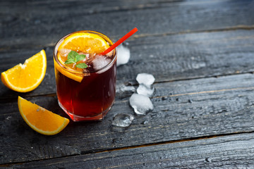 Negroni cocktail with ice and orange on dark background