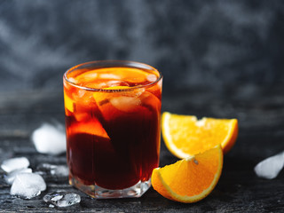 Negroni cocktail with ice and orange on dark background