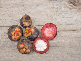Delicious ripe mangosteen (garcinia mangostana) on wood background.
