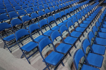 Many blue chairs stand in a row before the event