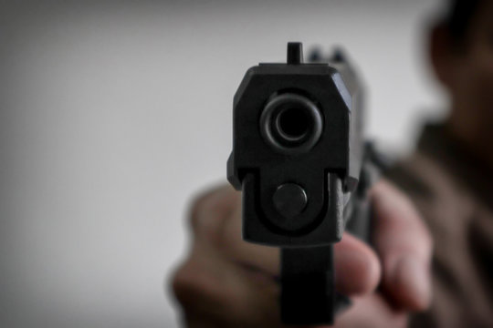 Gunman aiming his target.terrorism shoots a pistrol handgun.Criminal murder and violent concept - Film grain effect