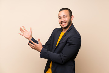 Colombian man over isolated background extending hands to the side for inviting to come