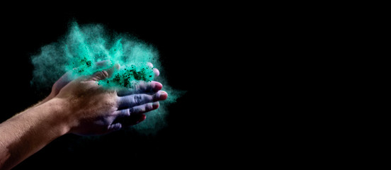 Colored holi powder in woman hands on black background