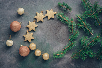 Christmas beautiful background from branches of spruce, golden balls and stars on a dark textured rustic background. Top view, flat lay, copy space.