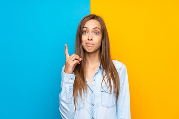 Young woman over colorful background pointing with the index finger a great idea