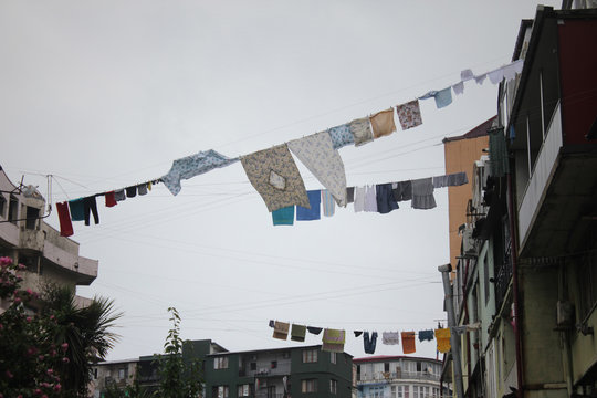 Clothes and sheets hanging on a rope between buildings on the street