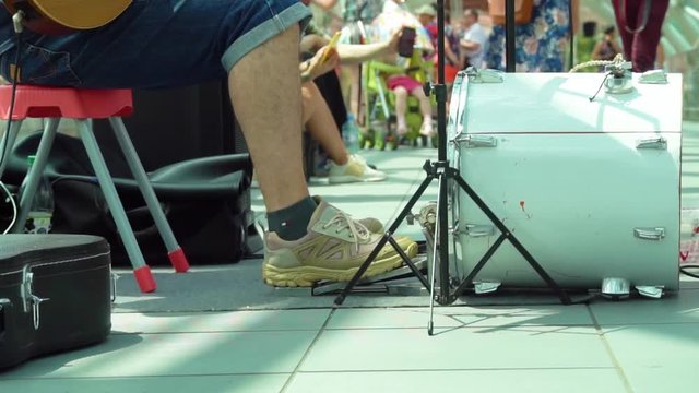 Close up drummer legs on the bass drum pedal outdoors on a sunny day. Street musician playing in the park. slow motion