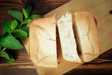 Tasty baked curd cheese dessert decorated mint leaves on wooden board. Homemade baked pudding.