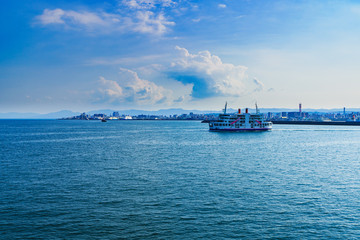 [鹿児島市の交通イメージ] 初夏の快晴の鹿児島港を背景に，桜島に向かう桜島フェリー