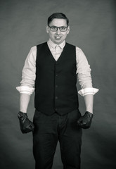 Photography in the Studio. A young man with glasses, wearing a shirt and a vest. On the hands of dressed leather gloves off.