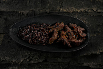 Korean-style bbq beef with black rice on a black wooden table. Directly above top view shot.