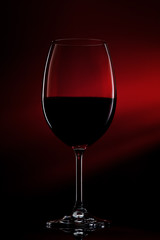 Silhouette of glass of red wine on black to red gradient background. Close-up studio shot.