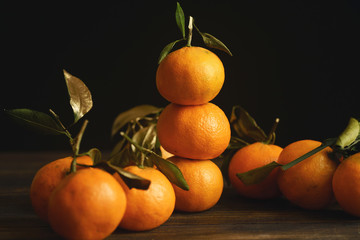 Tangerine pyramide with golden decorated leaves on dark background