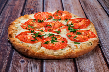 pizza with tomatoes is on a wooden table