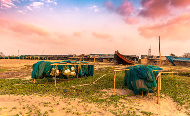 Fishing nets are lined up at the seashore overlooking the wooden boats .