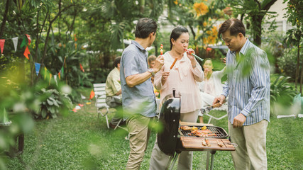 Family and Friends Gathered Together at the Table.Cooking bbq outdoor for a group of friends.Big Family Garden Party Celebration.Diverse Neighbors Drinking Party Yard Concept.