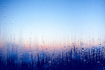 Clear water drops on the surface of the glass window. Color transition .Light blue, white, pink, dark blue shades. Perfect background for the artistic collages and illustrations.