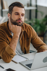 handsome man in shirt listening music and looking away