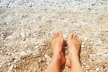 Female feet on a beach in a summer sunny day, close up. Vacation at the sea